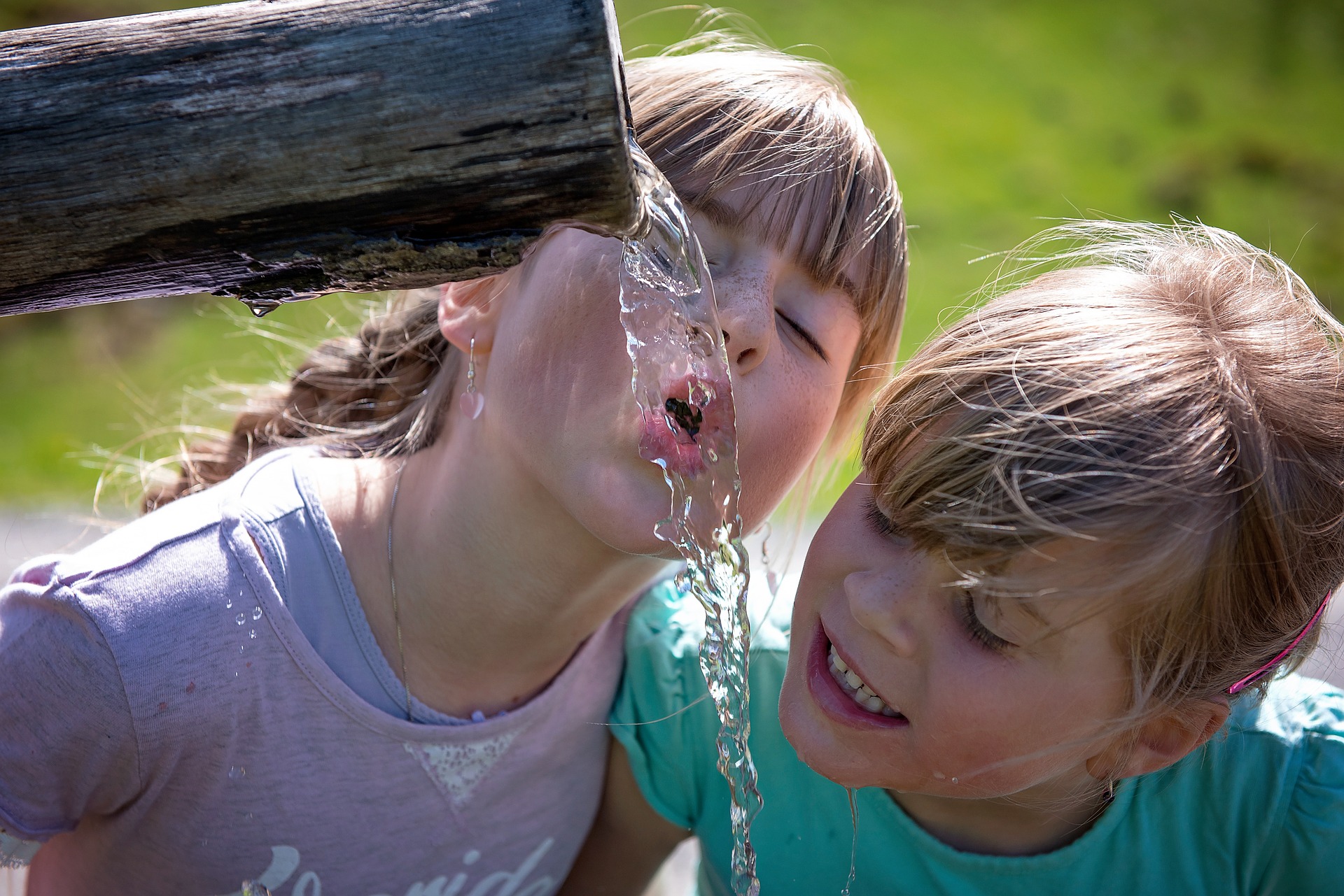 Zwei Kinder trinken aus einem öffentlichen Trinkwasserspender