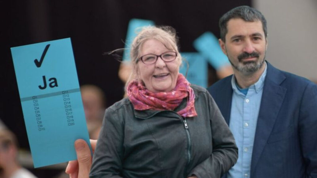 Sandra Leurs und Hèlder Aguiar vor hochgerechnet Stimmkarten mit Ja